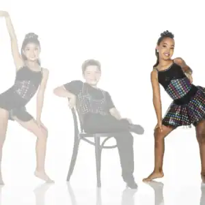 Three young dancers in colorful polka-dot costumes posing