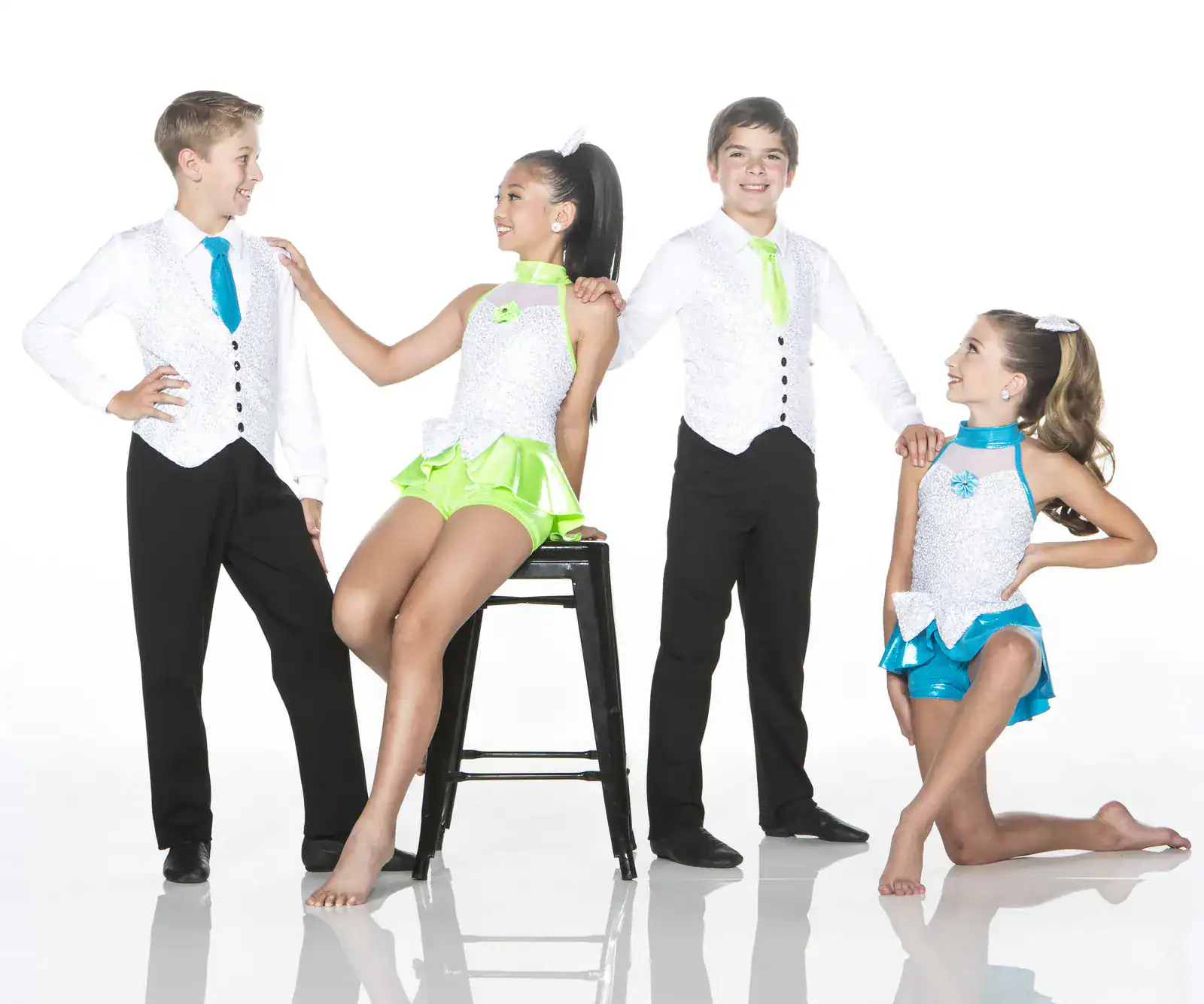 Four children wearing colorful dance costumes pose in studio.
