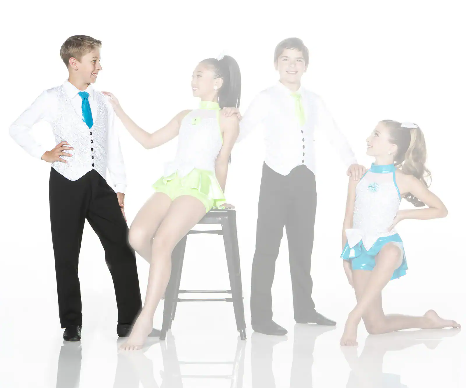 Four young dancers pose in colorful costumes against white background.