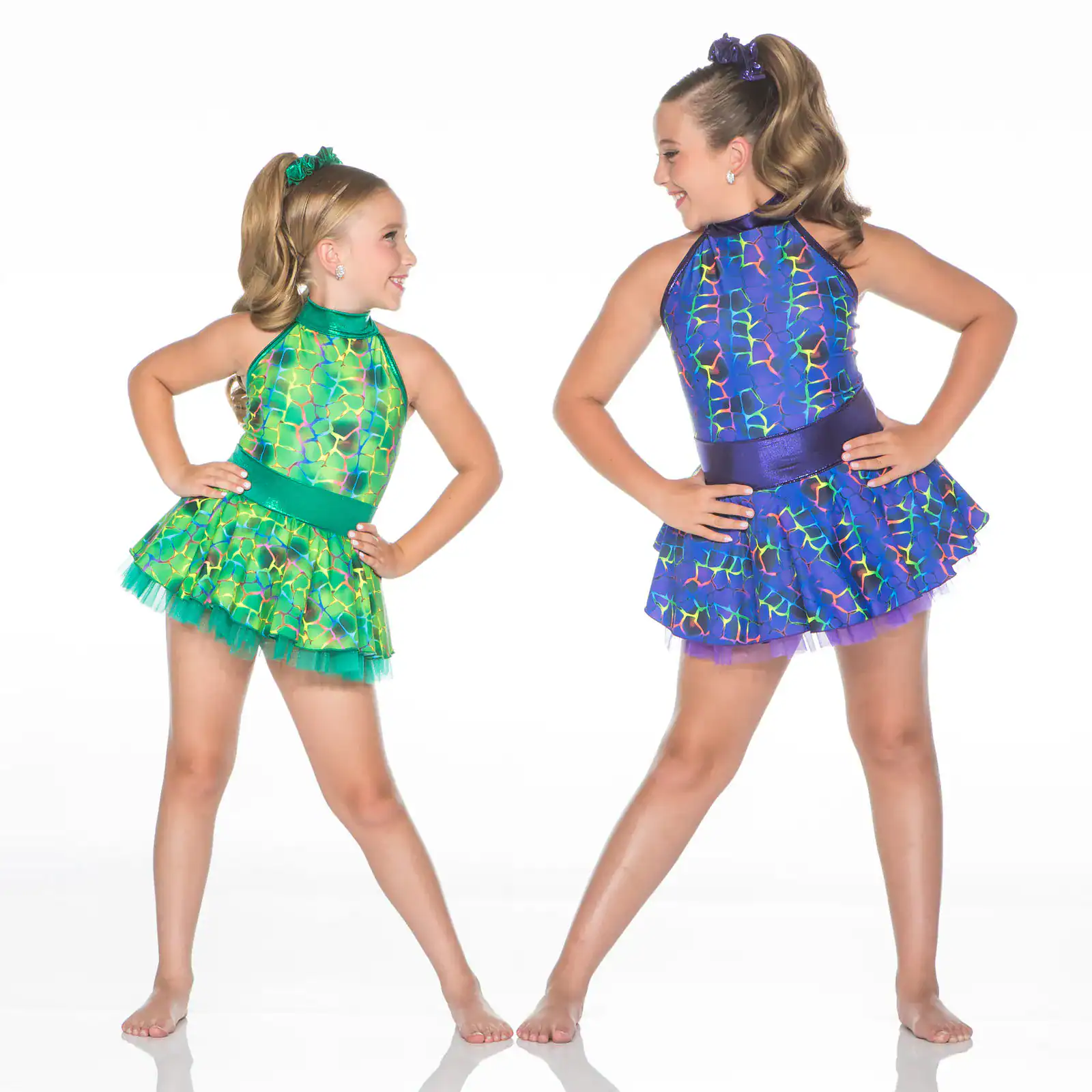 Two young dancers wearing colorful patterned costumes pose together.