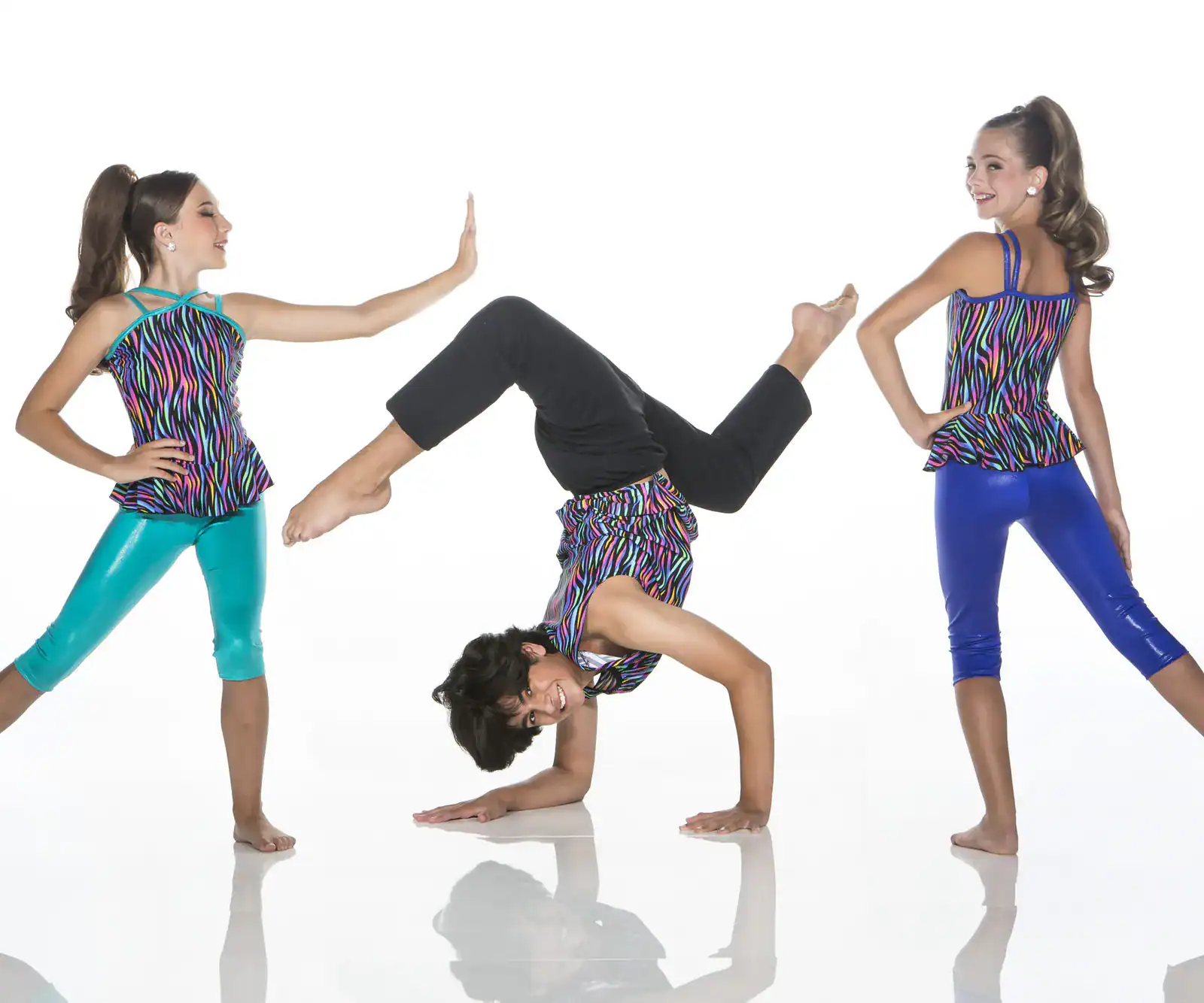 Three girls modeling colorful dancewear, one doing a handstand.
