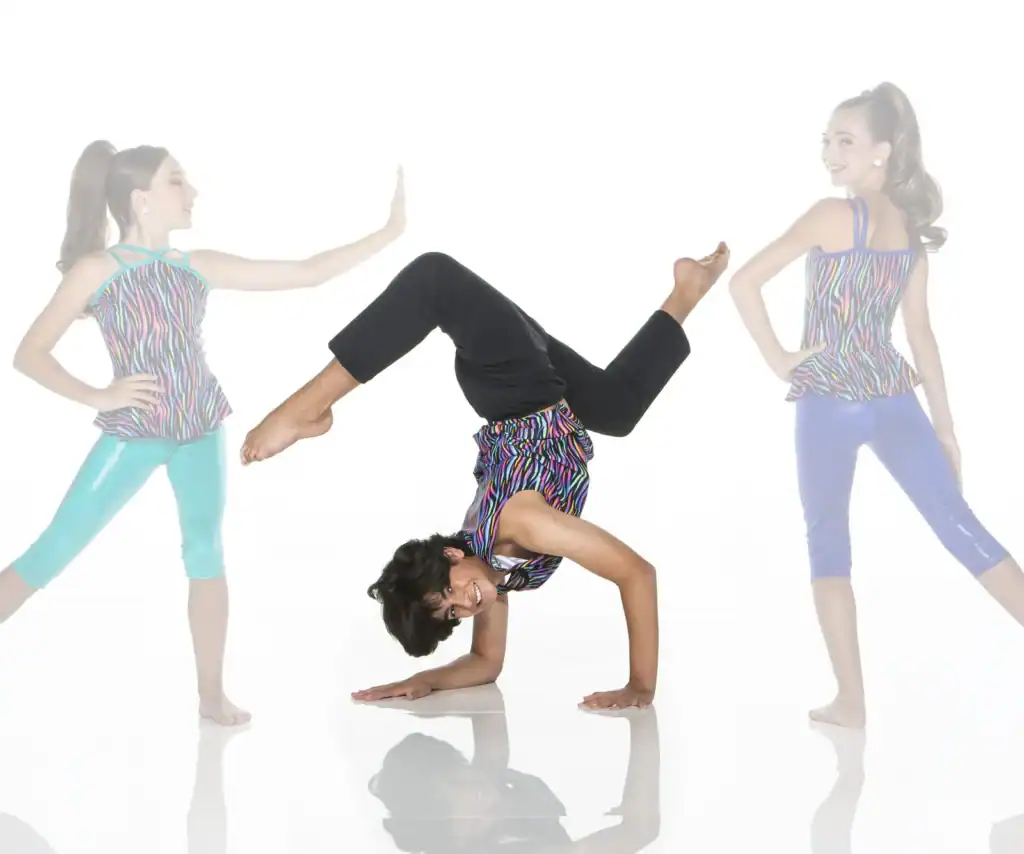 Three young dancers posing in colorful outfits against white background