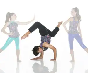 Three young dancers posing in colorful outfits against white background