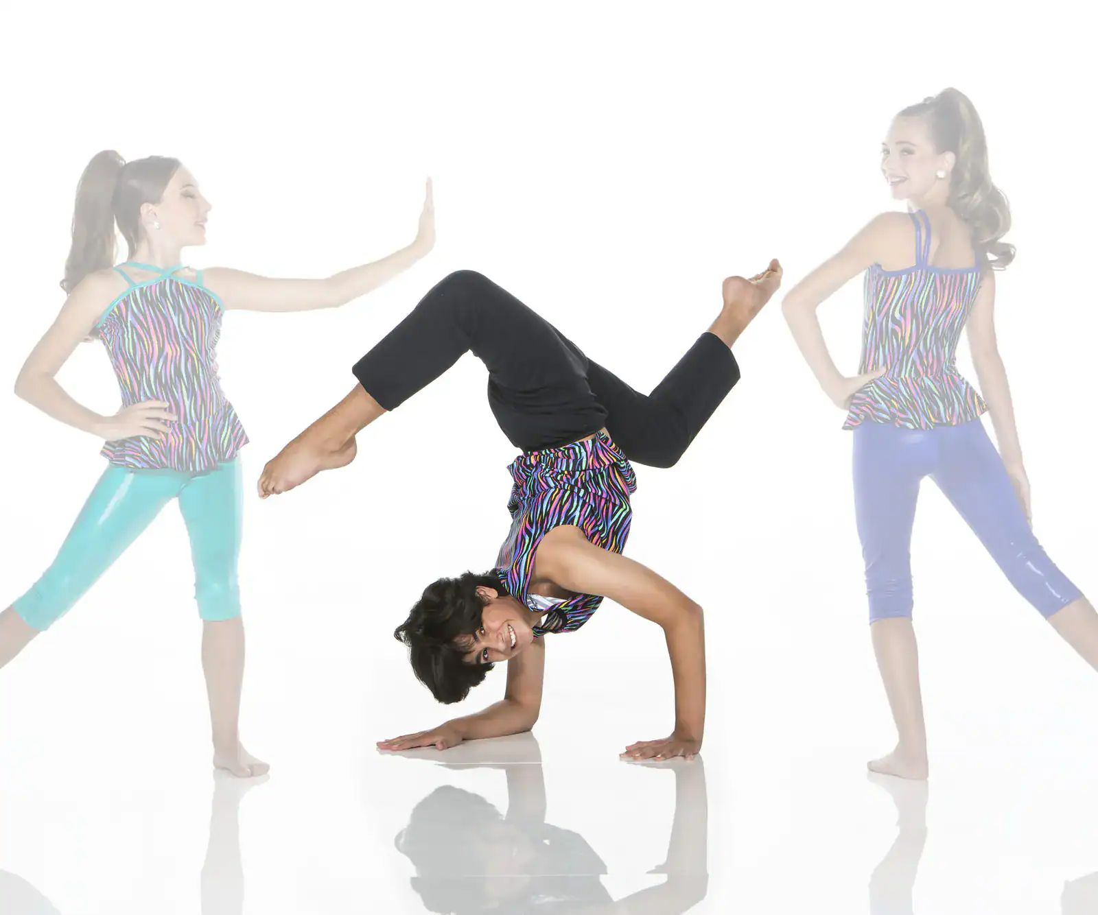 Three young dancers posing in colorful outfits against white background