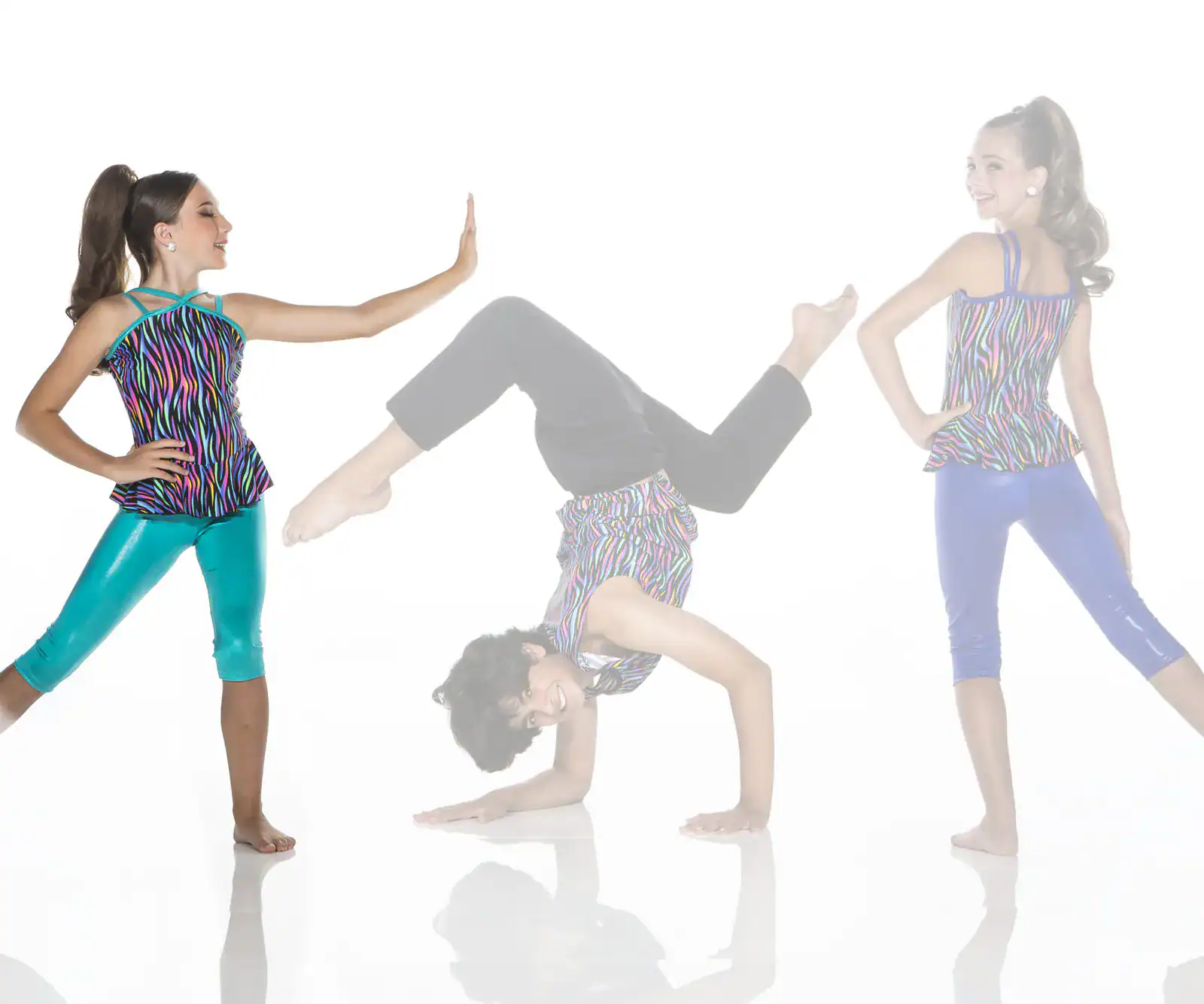Three girls in colorful dancewear pose against a white background.