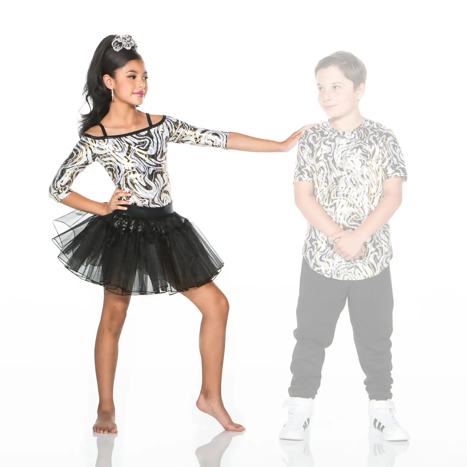 Girl in tutu touches boy wearing matching patterned shirt
