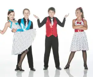Young dancers wearing colorful polka-dot costumes pose together