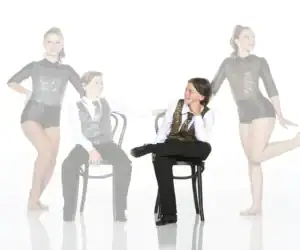 Four young dancers in sparkling costumes posing in studio
