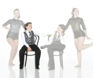Four young dancers in glittery costumes posing in studio
