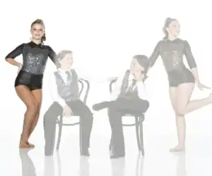Four young dancers in sparkly black costumes posing in studio