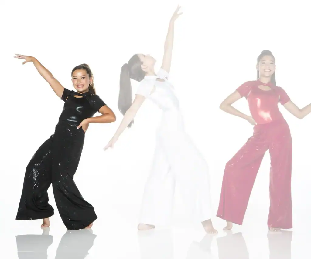 Three girls dancing in sparkly jumpsuits on white background