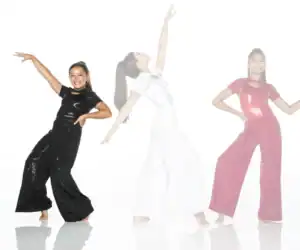 Three girls dancing in sparkly jumpsuits on white background
