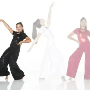 Three girls dancing in sparkly jumpsuits on white background