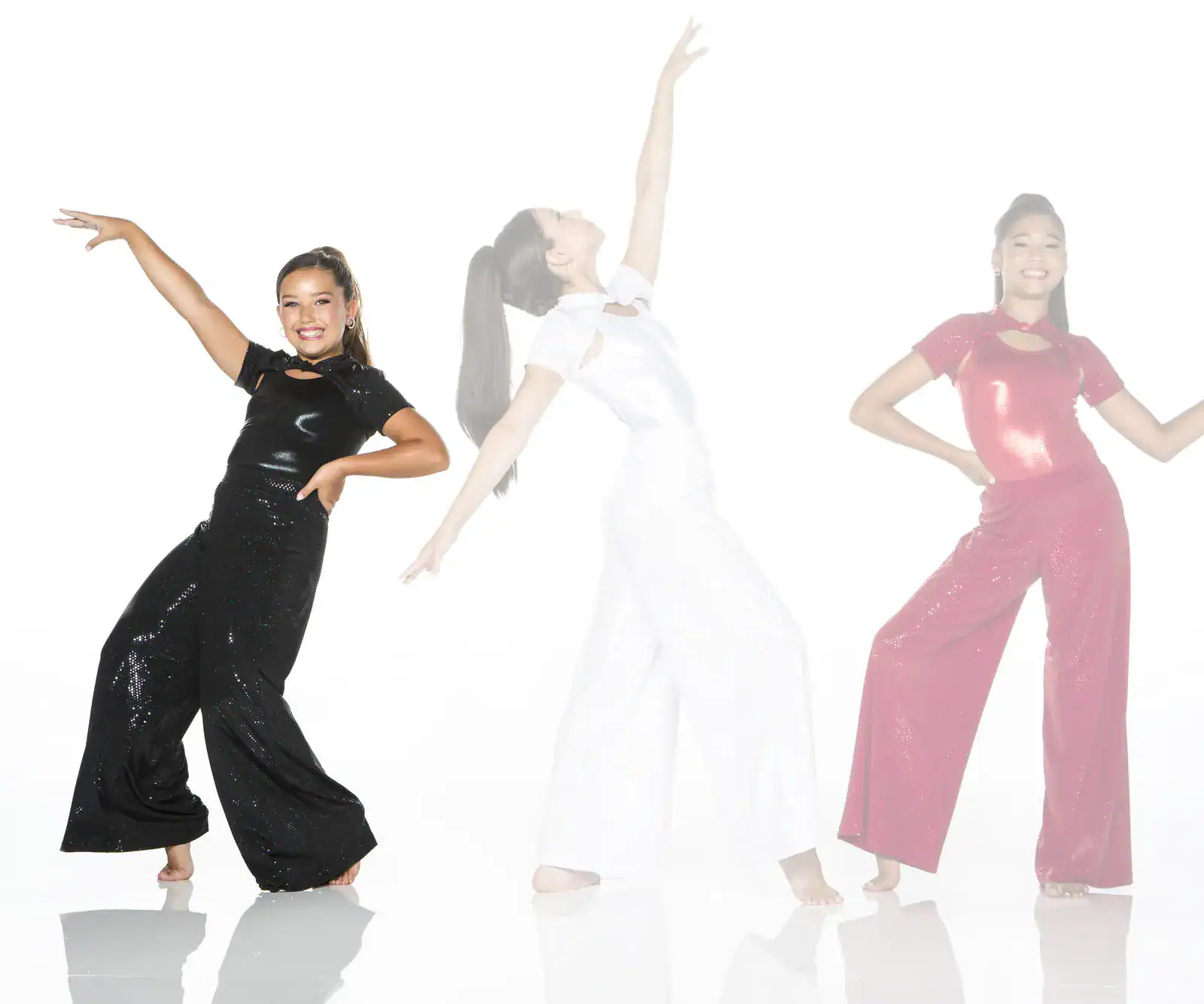 Three girls dancing in sparkly jumpsuits on white background