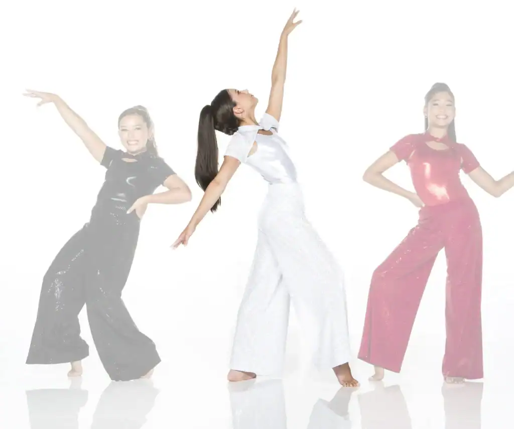 Three women dancing in sparkling black, white, and pink outfits