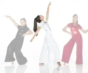 Three women dancing in sparkling black, white, and pink outfits