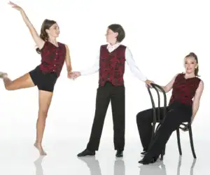 Three performers wearing red patterned vests pose in studio