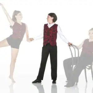 Dancers in matching red vests pose beside chair