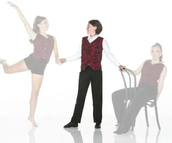 Dancers in matching red vests pose beside chair