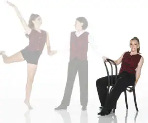 Three dancers wearing matching red patterned costumes pose together.