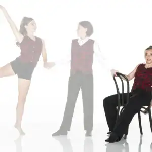 Three dancers wearing matching red patterned costumes pose together.