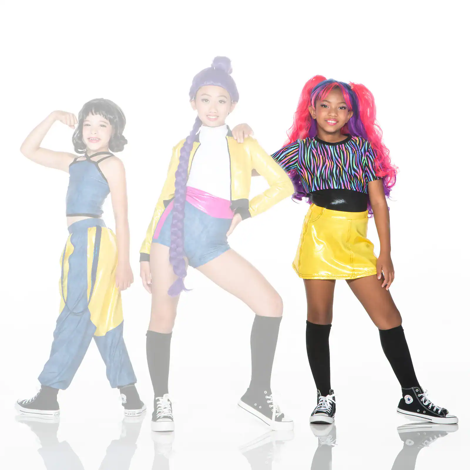 Three girls pose in colorful, retro-inspired fashion outfits.
