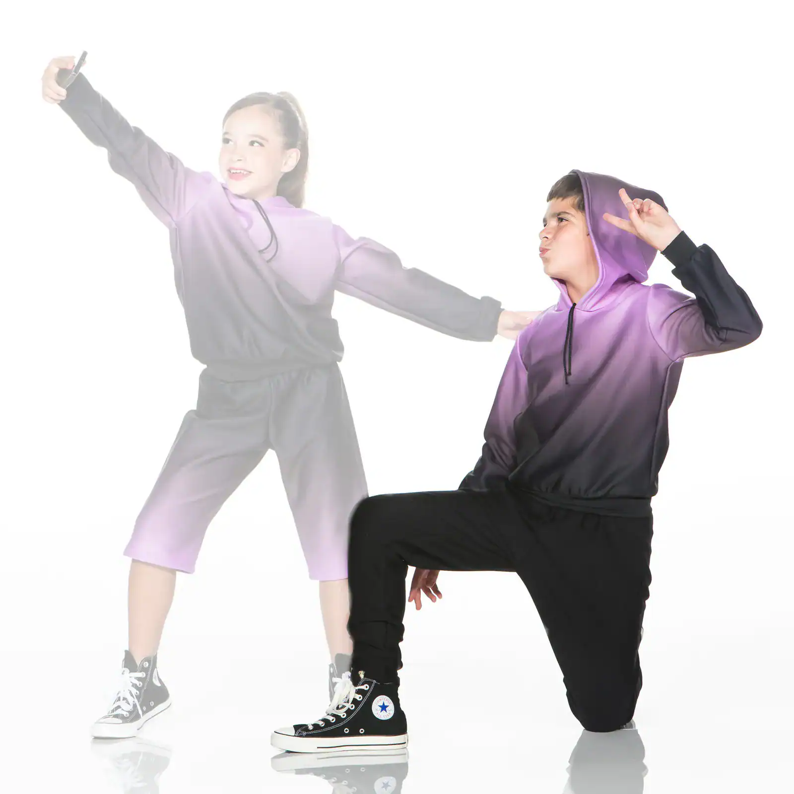 Two children in purple hoodies posing against white background