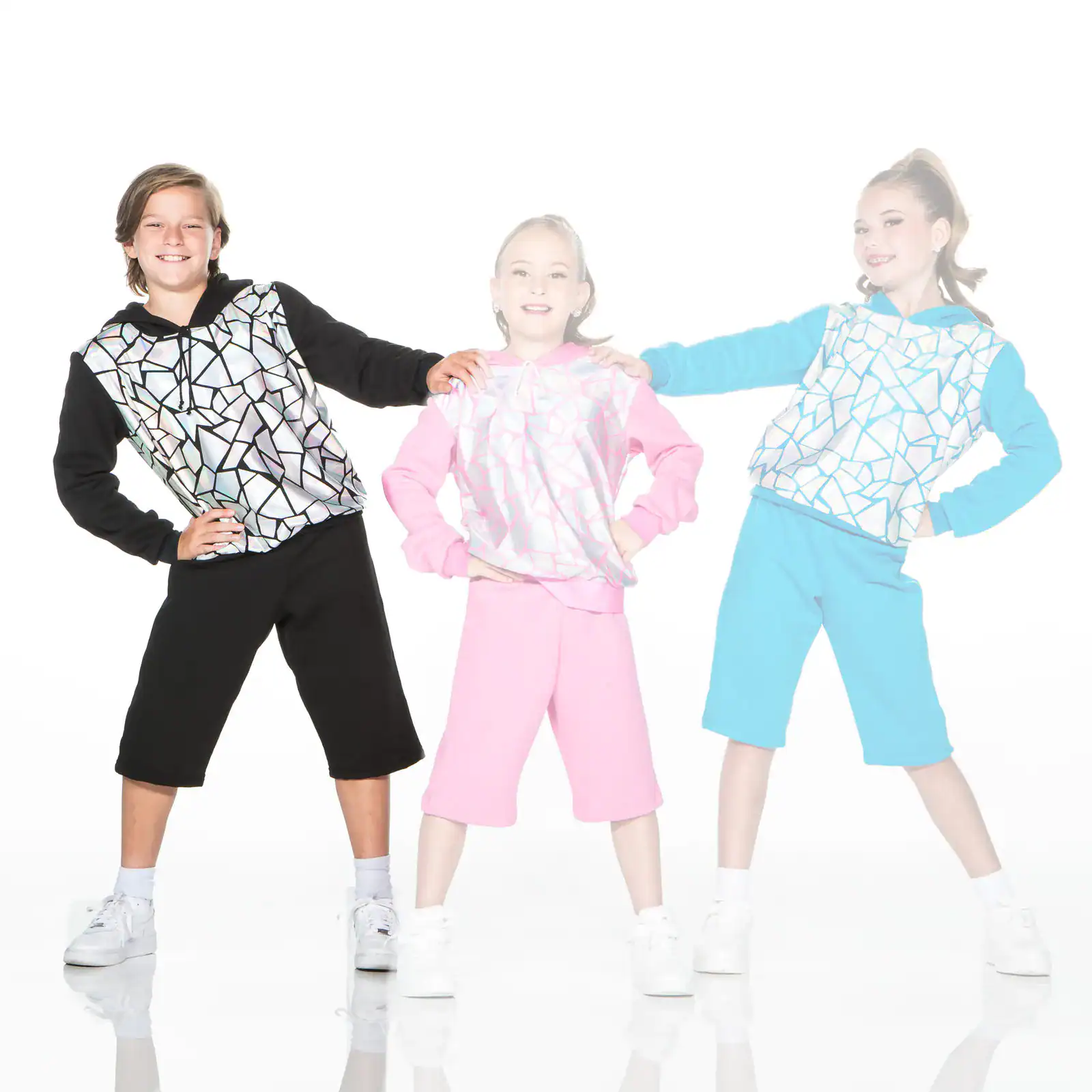 Three children modeling colorful geometric-patterned hoodies and shorts.