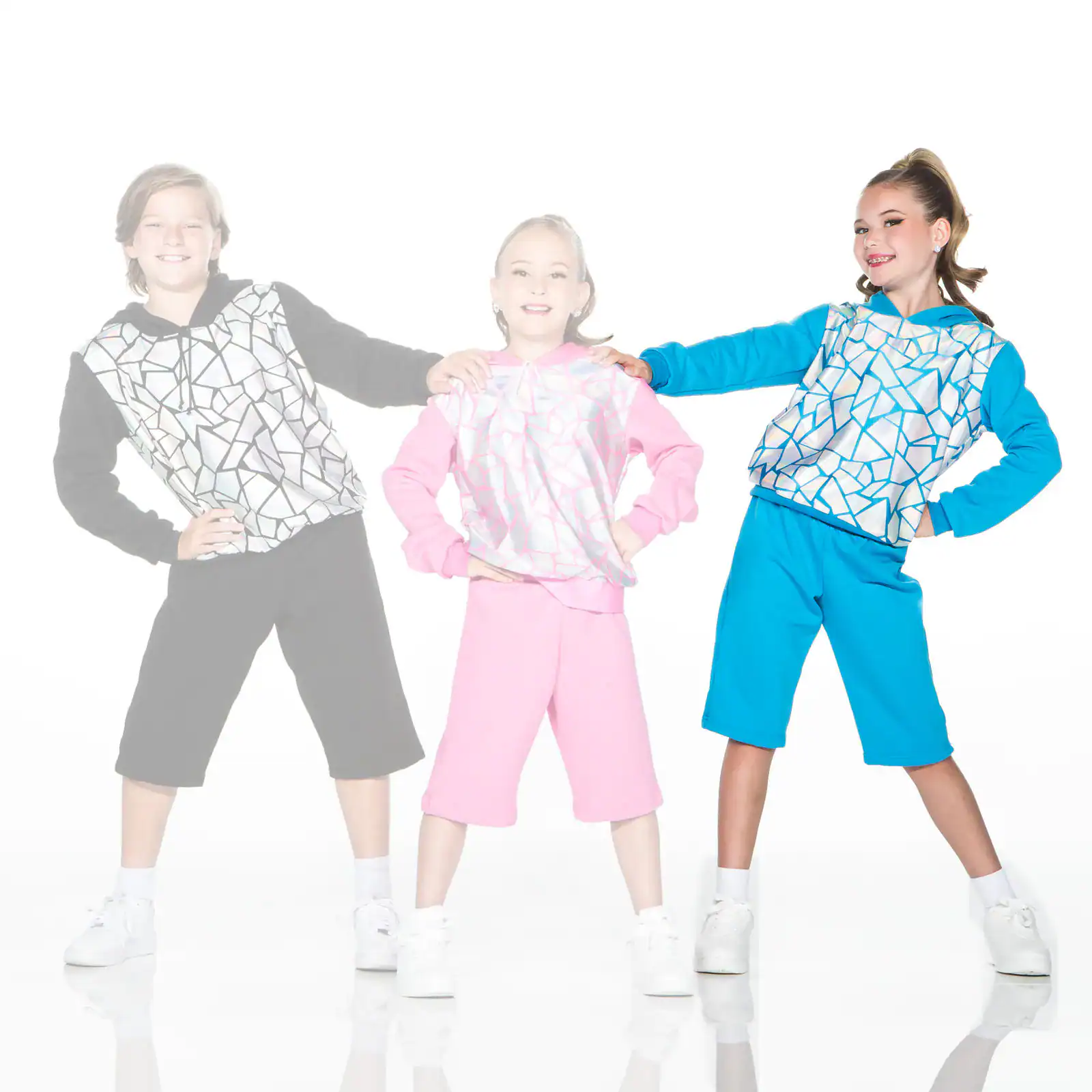 Three children wearing colorful geometric-patterned hoodies and shorts