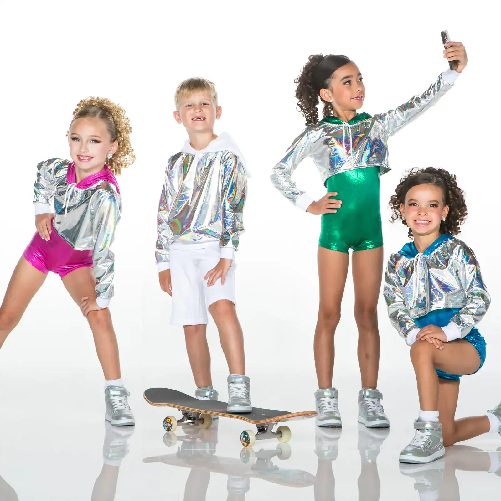Four children wearing metallic hoodies and colorful outfits pose together.