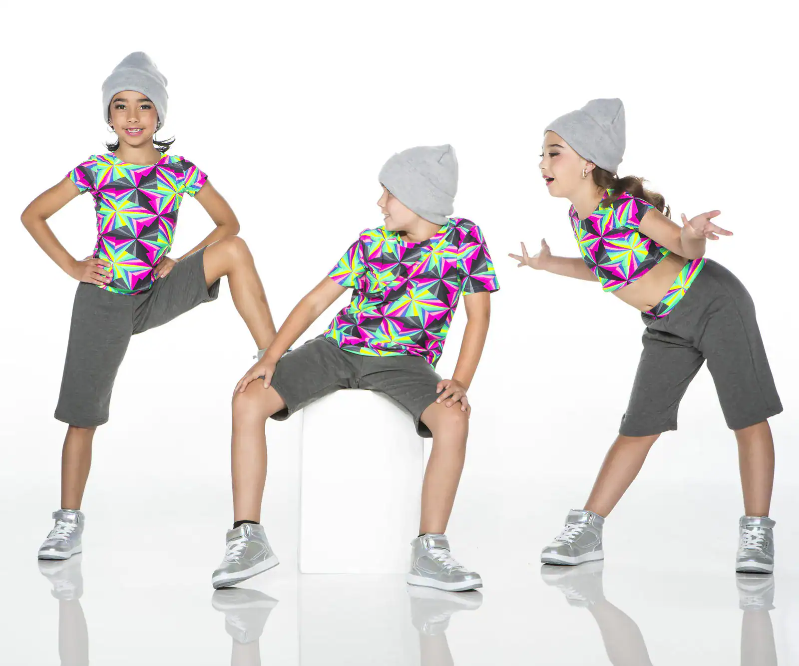 Three girls in colorful geometric shirts and gray beanies