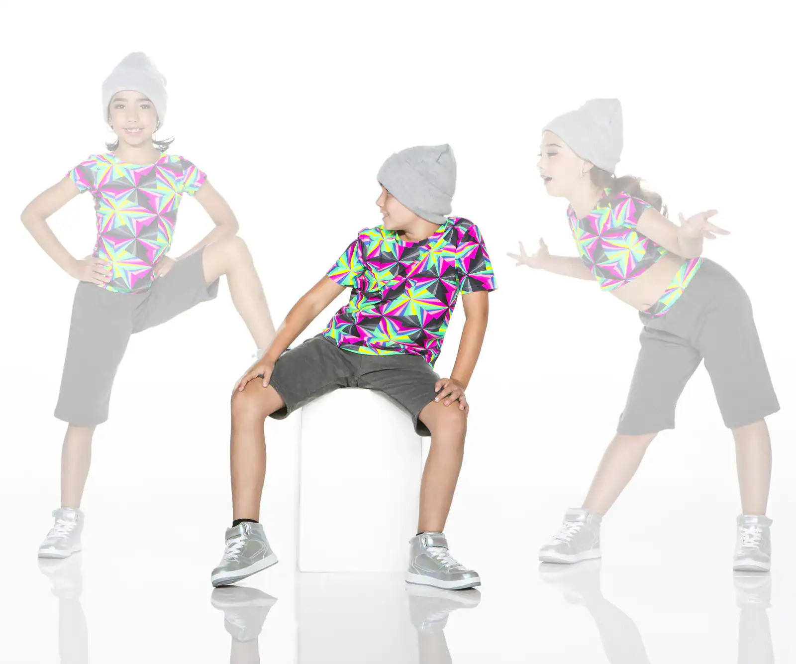 Three children modeling colorful geometric shirts and gray beanies
