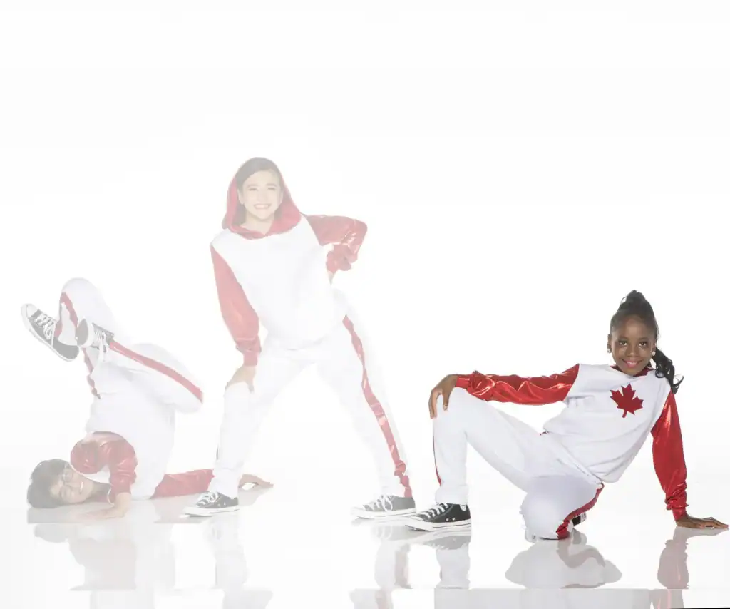 Three dancers in white and red Canadian-themed costumes posing.