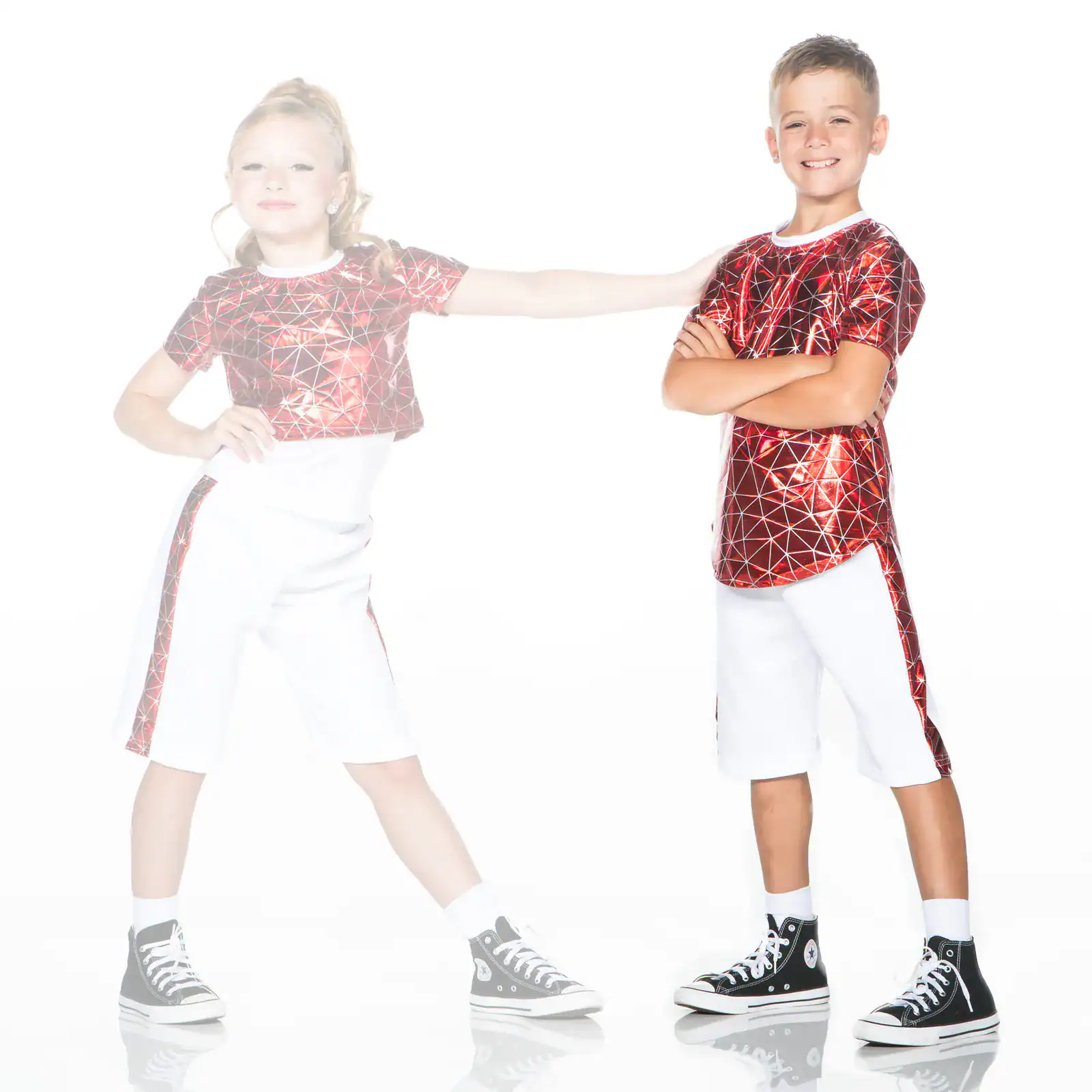 Two children wearing red metallic shirts and white shorts