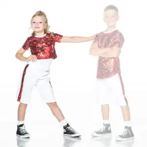 Two children wear matching red patterned shirts and white shorts.