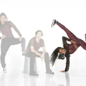 Three dancers pose in coordinated red and black outfits.