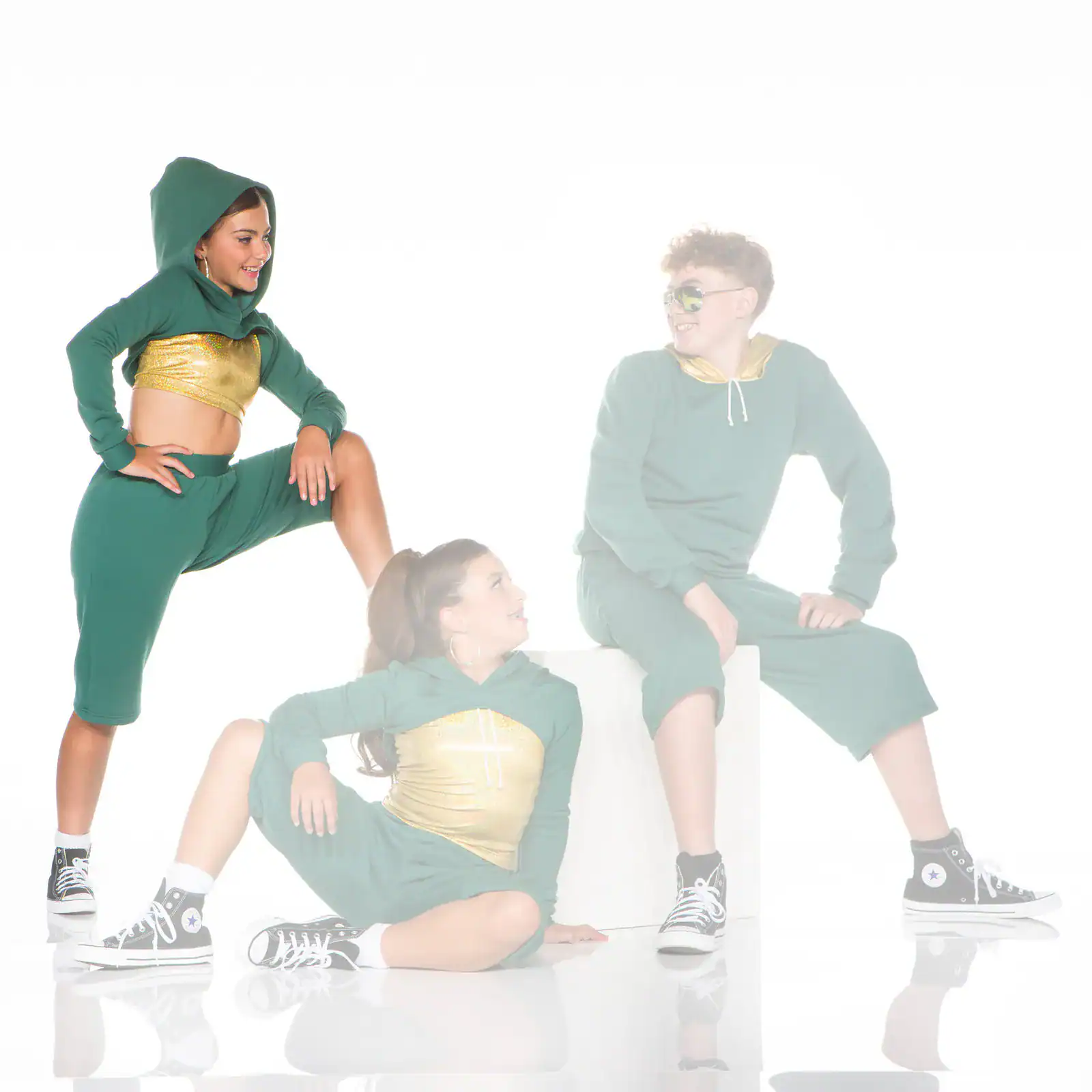 Three dancers in green and gold outfits posing together