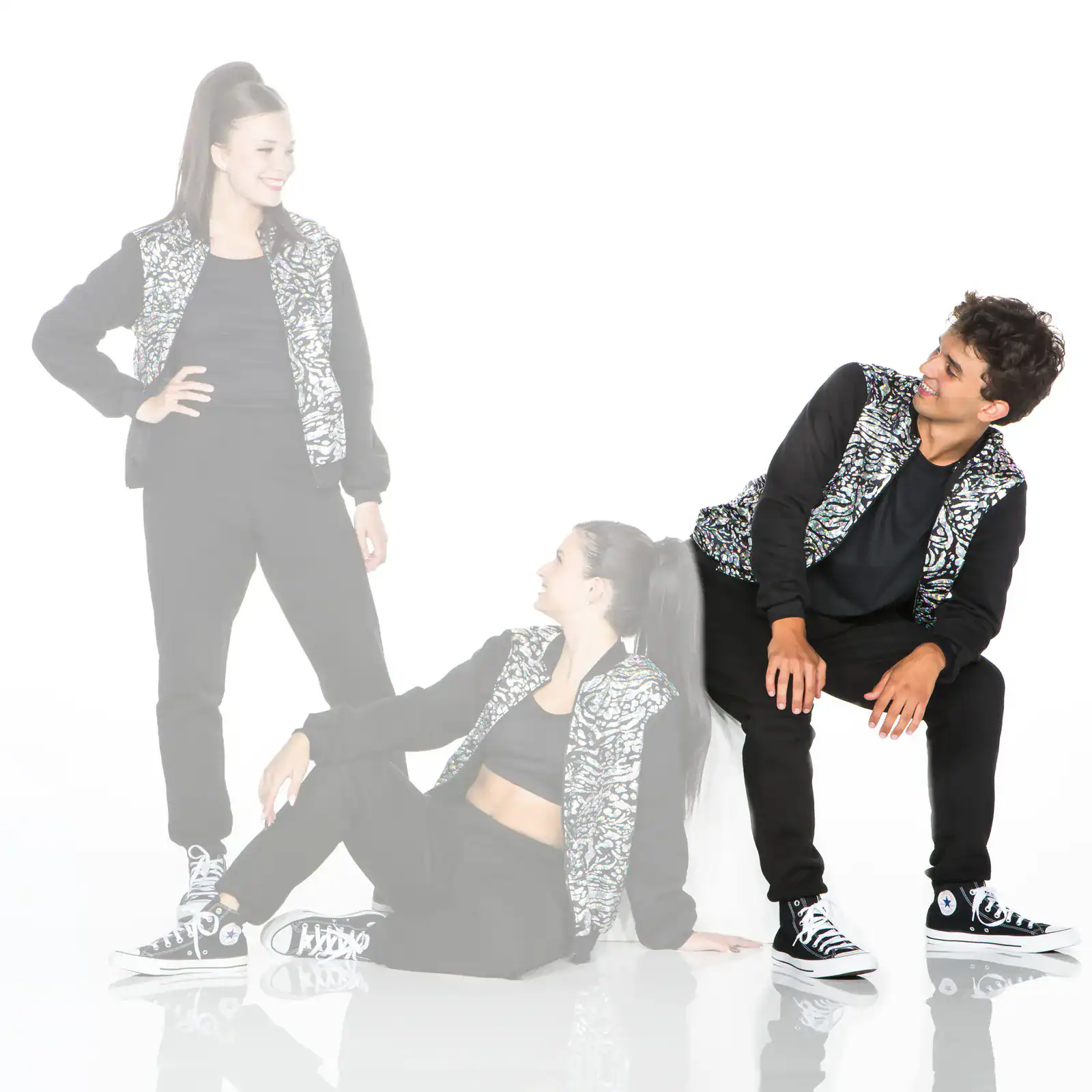 Three dancers in matching black outfits and patterned vests