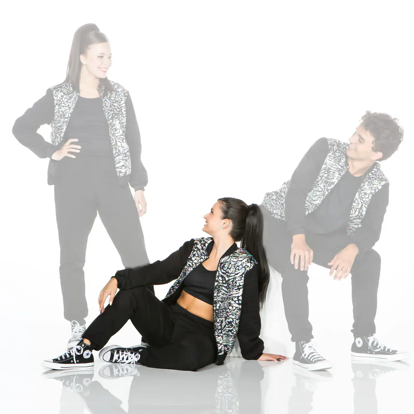 Three dancers wearing matching patterned vests and black outfits.