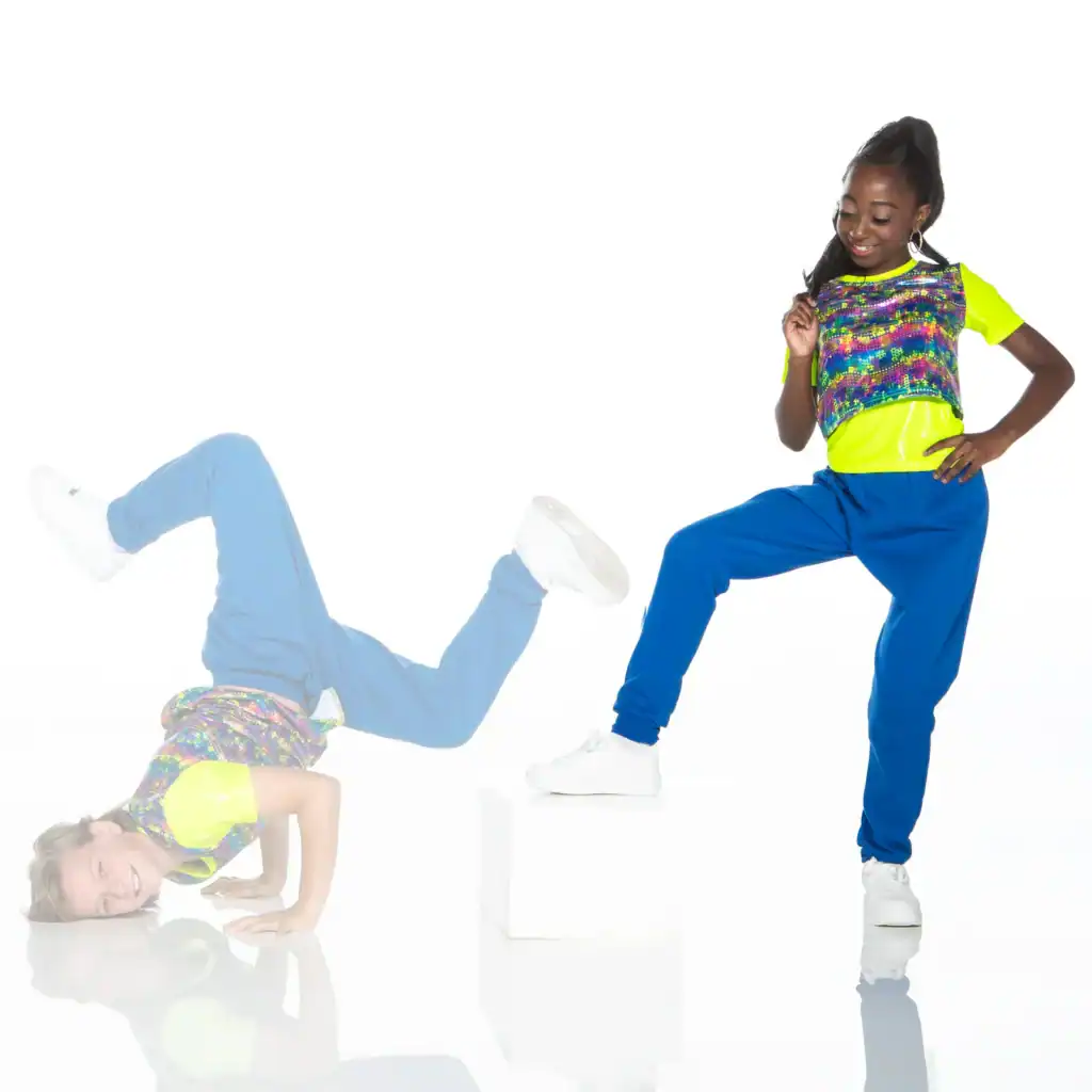 Two dancers posing in colorful streetwear against white background.