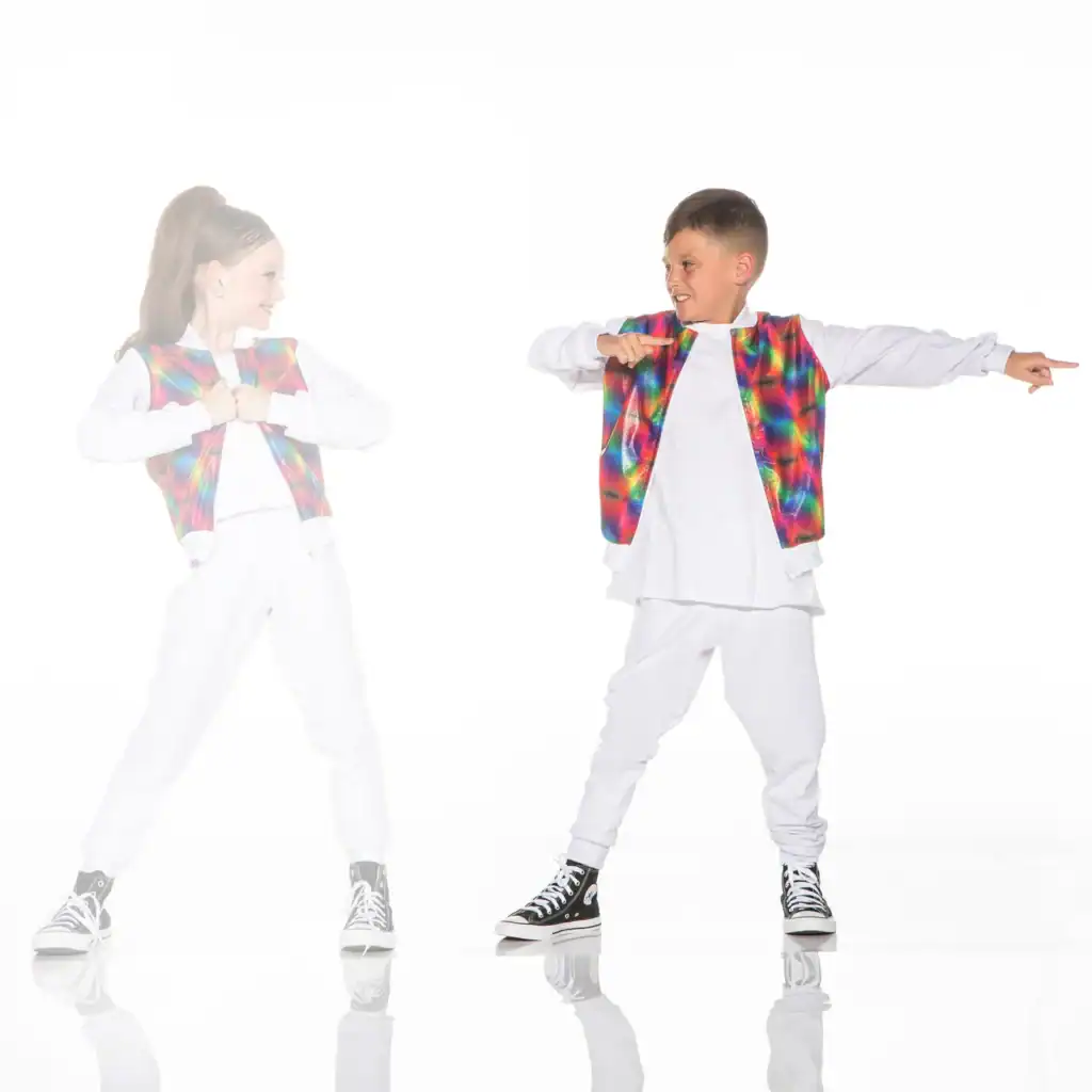 Two children wearing colorful vests and white outfits dance.