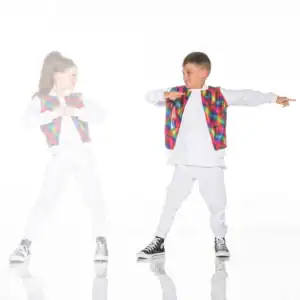 Two children wearing colorful vests and white outfits dance.