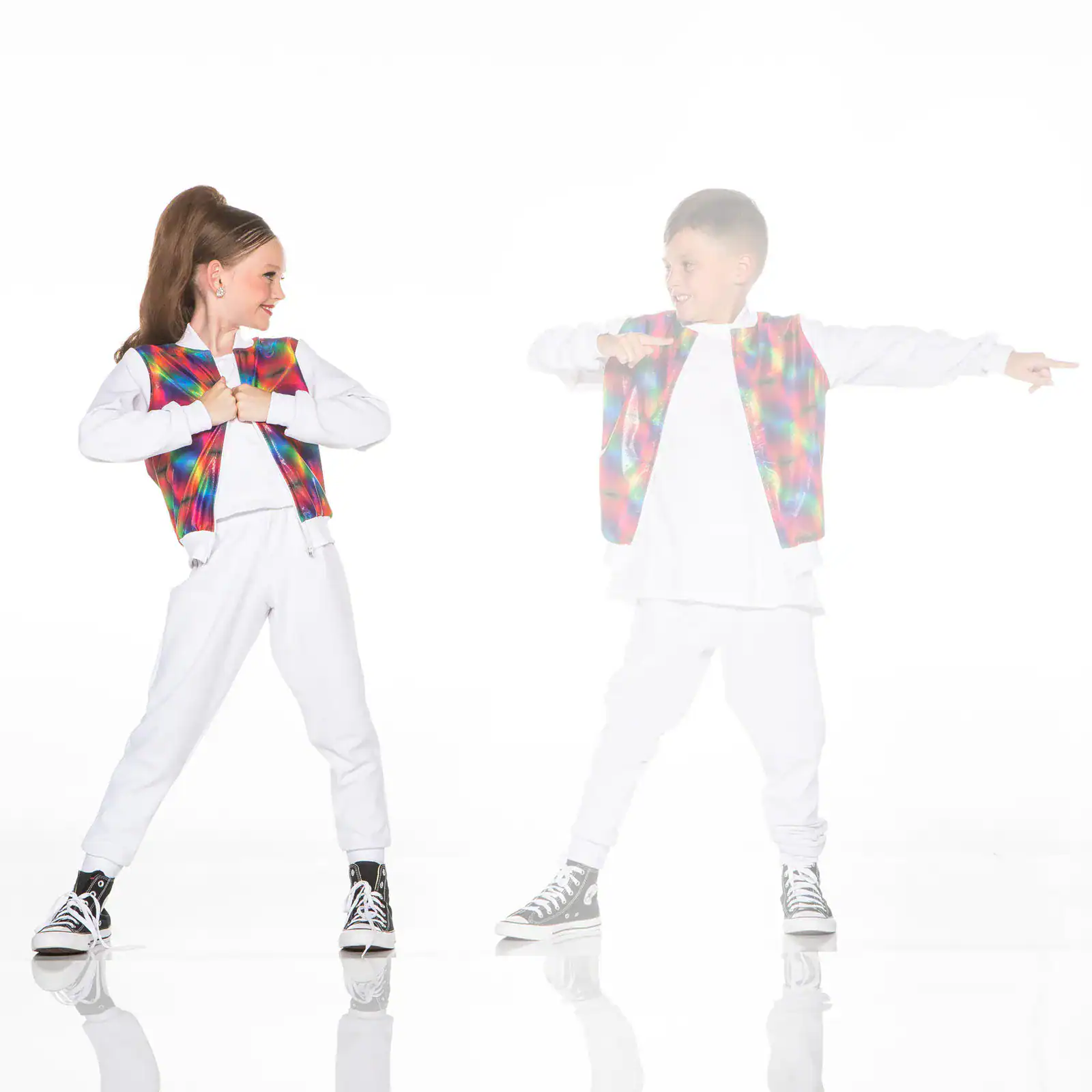 Two children dance in colorful vests against white background.