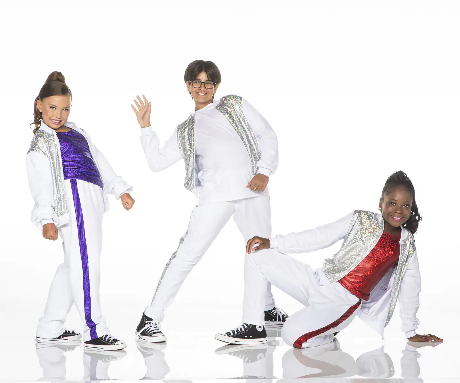Three children posing in sparkling white dance outfits