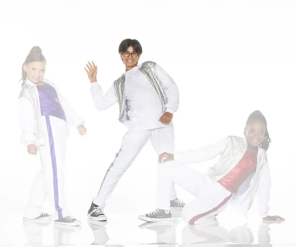 Three children posing in sparkling white dance outfits