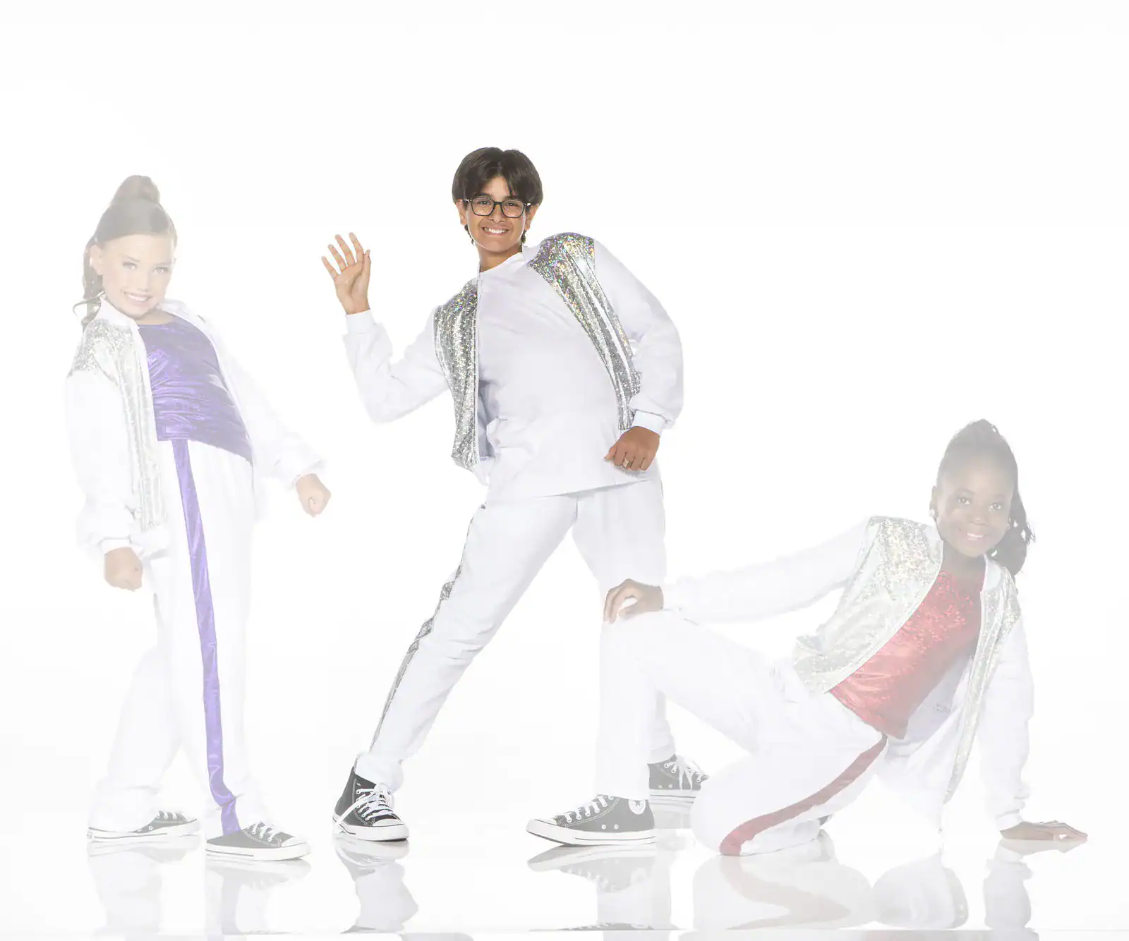 Three children posing in sparkling white dance outfits