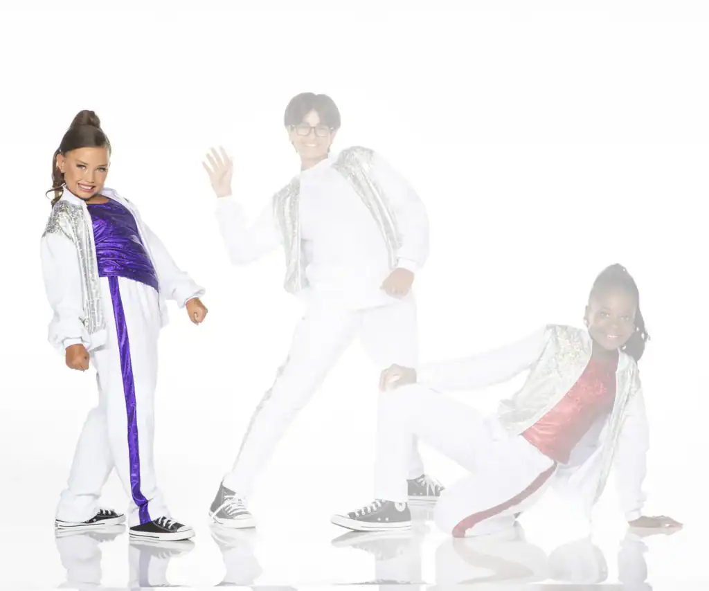 Three children posing in colorful dance outfits on white background