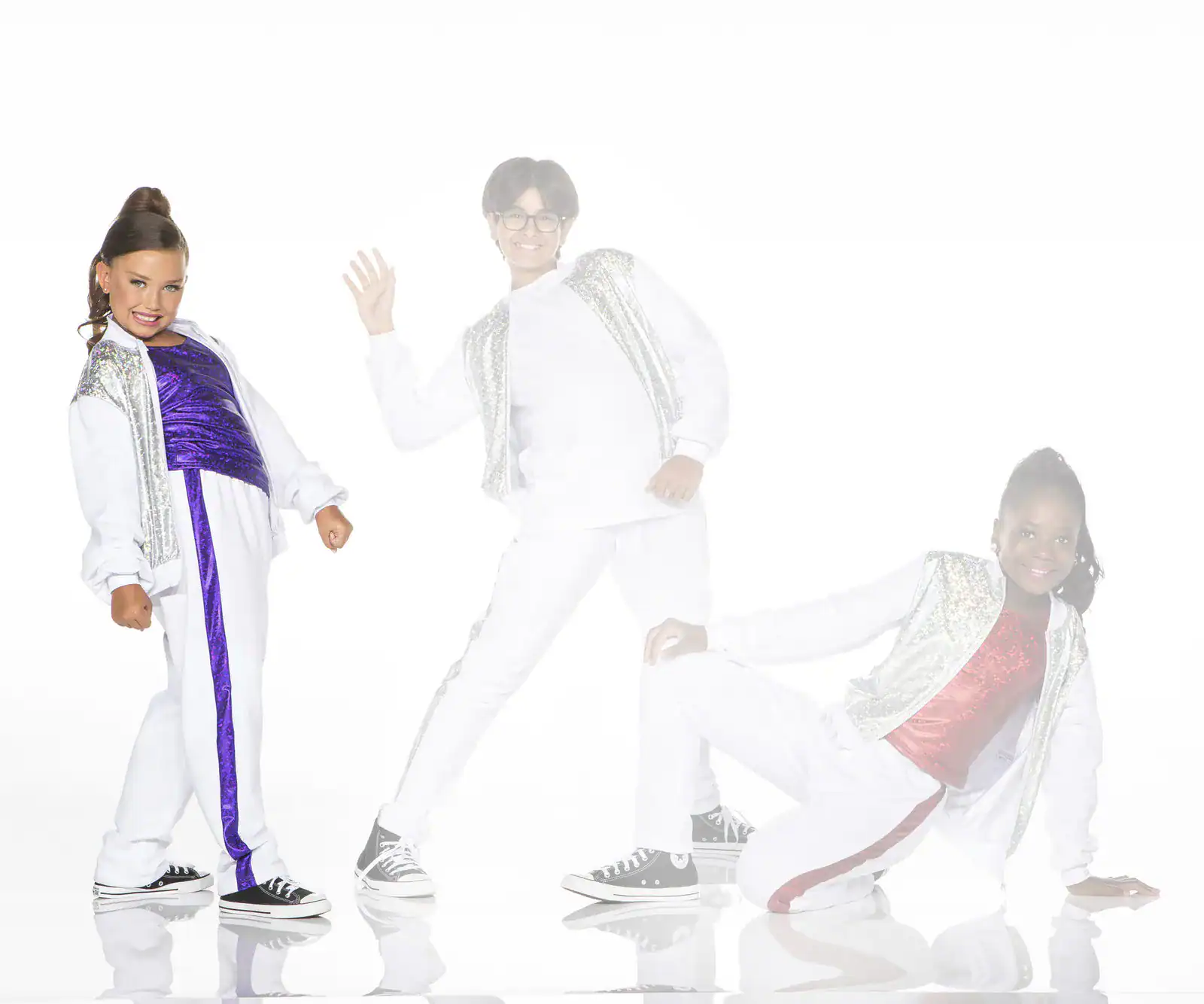 Three children posing in colorful dance outfits on white background