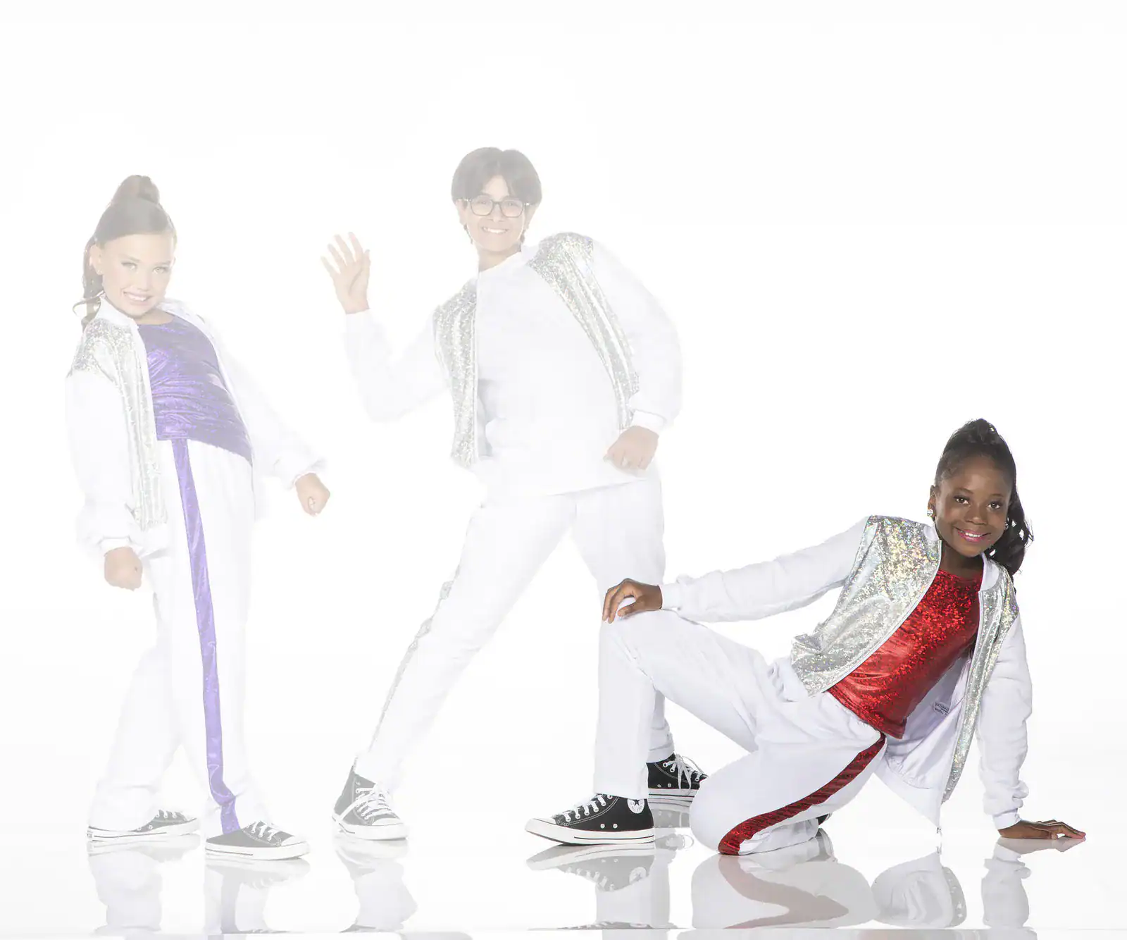 Three children posing in white and sequined dance outfits