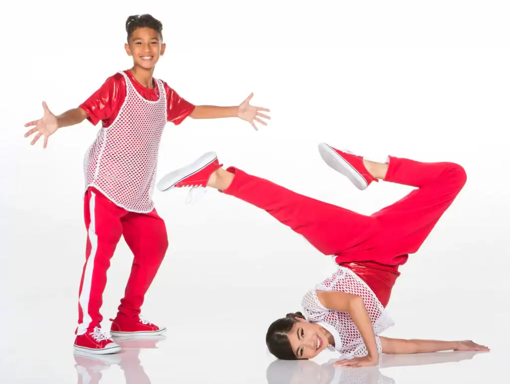 Two young dancers in red outfits pose on white background.